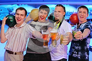 Four men hold balls and glasses of beer