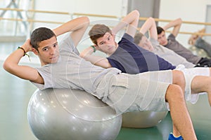 Four men leaning on aerobic balls twisting towards camera