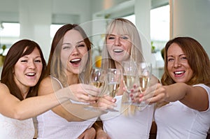 Four merry women partying and toasting