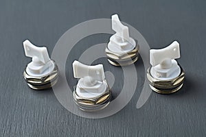 Four metal air valves with white plastic handle for to vent excess air and pressure from heater radiator in room