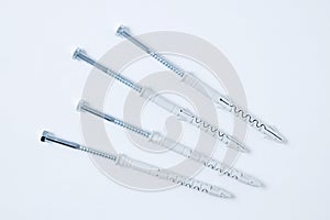 Four metal dowel-nail with  plastic box on a white background