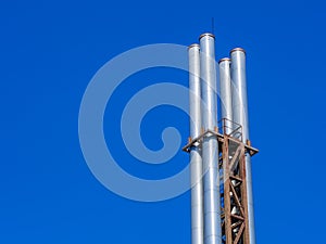 Four metal pipes against a blue sky.