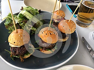 Four mini burger sliders on plate at restaurant