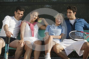 Four mixed doubles tennis players on bench