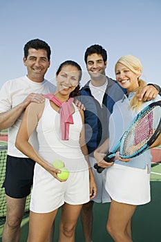 Four mixed doubles tennis players by net at tennis court portrait