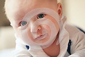 Four months old baby boy crawling on bed, detail on his head and face expression