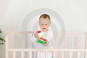 Four months old little boy playing in baby bed. Toys are officially property released