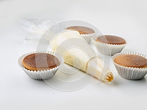 Four muffins and a pastry bag seen frontally