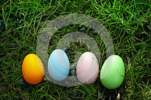 Four multi-colored Easter eggs lie in a line in the green grass