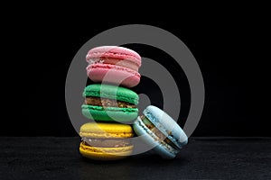 Four multi-colored homemade natural products macaroon on a black background