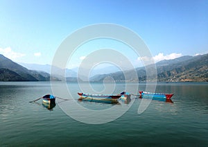 Four multicolore tourist boats of Lake Pheva, mountains and clouds