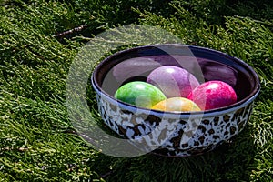 Four multicolored bright easter eggs in ceramic bowl