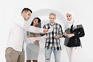 Four Multicultural College students friends, male and female, standing on a white background, while Caucasian guy gives