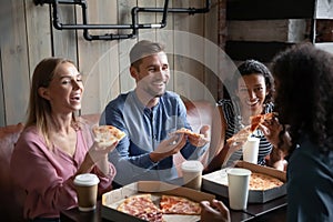 Four multiethnic best friends eat pizza drink coffee in cafe