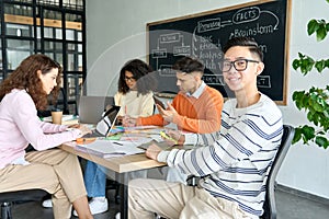 Four multiracial cheerful happy students studying together in classroom.