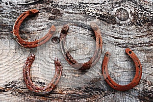 Four old rusty horseshoes on wooden ground