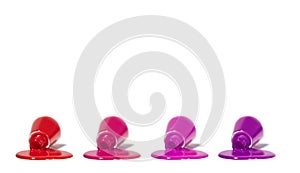 Four open nail polish bottles  on white background. Nail polish spilled from several bottles. Copy space