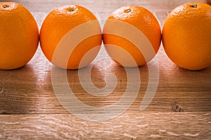 Four orange fruits organized in row on wooden