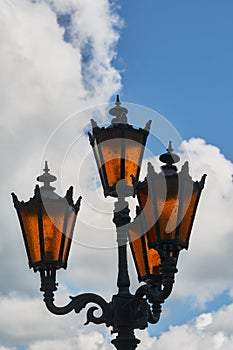 Four orange street lights on a background of clouds