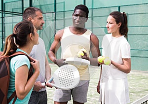 Four paddle tennis players talking on court