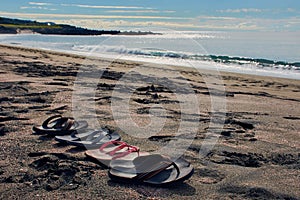 Four pair of flip flops at the beach