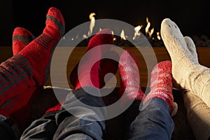 Four pairs feet in socks warming by fire