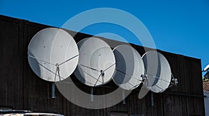 Four parabolic antennae on the facade of a building..