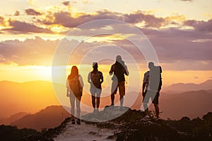 Four peope`s silhouettes on mountain top looks at sunset photo