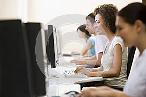 Four people in computer room typing and smiling