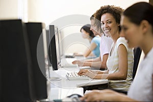 Four people in computer room typing and smiling