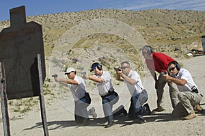 Four People Firing Guns At Shooting Range photo