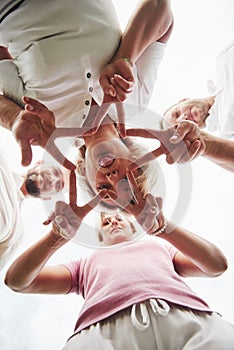 Four people fold hands together as a sign of their team work