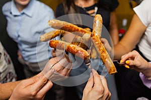 four people hold a hot dog together.