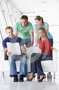 Four people in lobby looking at laptop smiling