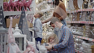 Four people in the supermarket. A family in medical masks in the store buys Christmas decorations and gifts in slow