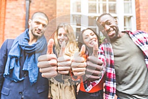 Four persons with different ethnicities showing thumbs up
