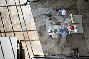 Four persons team of engineers talk together to review constuction material