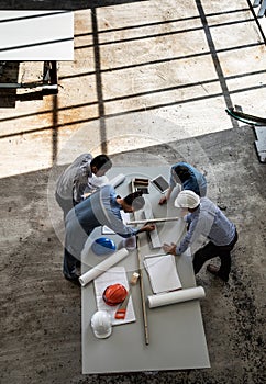 Four persons team of engineers talk together to review constuction material