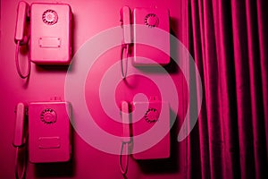 Four pink vintage telephone on a pink wall in pin-up style.