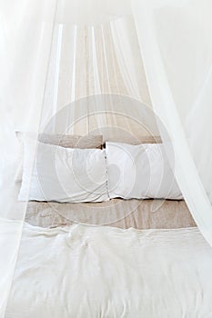 Four-poster bed with two pillows. Scandinavian simplicity design. Eco loft apartments.