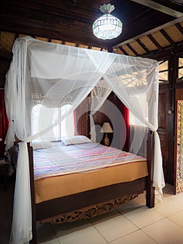 Four poster bed with white curtains in Indonesian bungalow