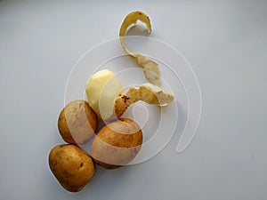 Four potatoes, one half peeled. isolated