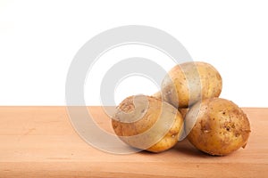 Four potatoes on wooden table