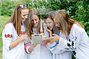 Four pretty happy teen girl friends and tablet computer