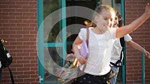 Four pupils are having fun after school lessons. They wear school uniform. School building is on background.