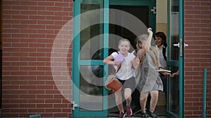 Four pupils are having fun after school lessons. They wear school uniform. School building is on background.