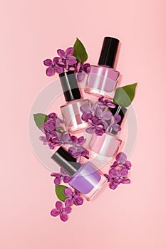 Four purple nail polish bottles on purple background. Set of purple nail polish bottles with purple lilac decoration