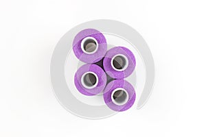 Four purple sewing threads on a white coils on a white background. Sewing supplies