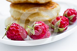 Four raspberries on plate, pancakes background