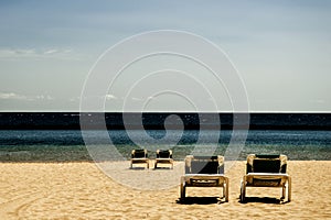 Four reclining chairs on a beach (contrast)